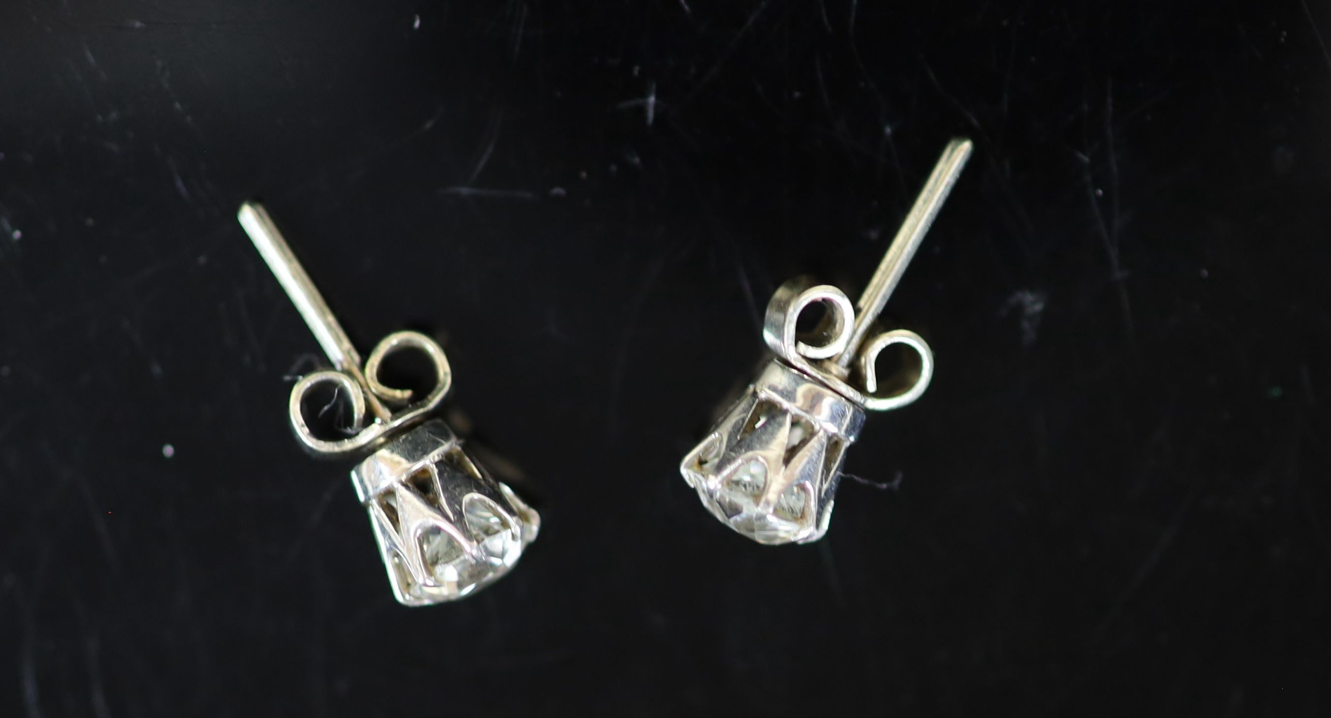 A pair of white gold and solitaire diamond ear studs